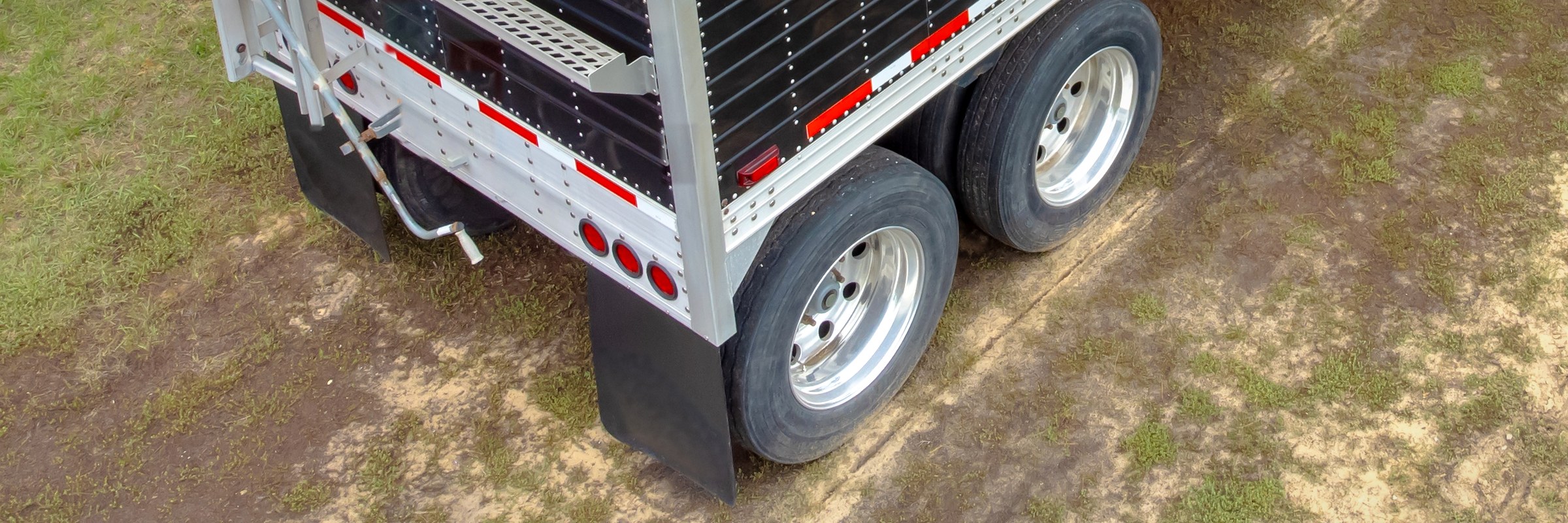 Rear of a grain hopper trailer with plain black mud flaps (illustrative photo)