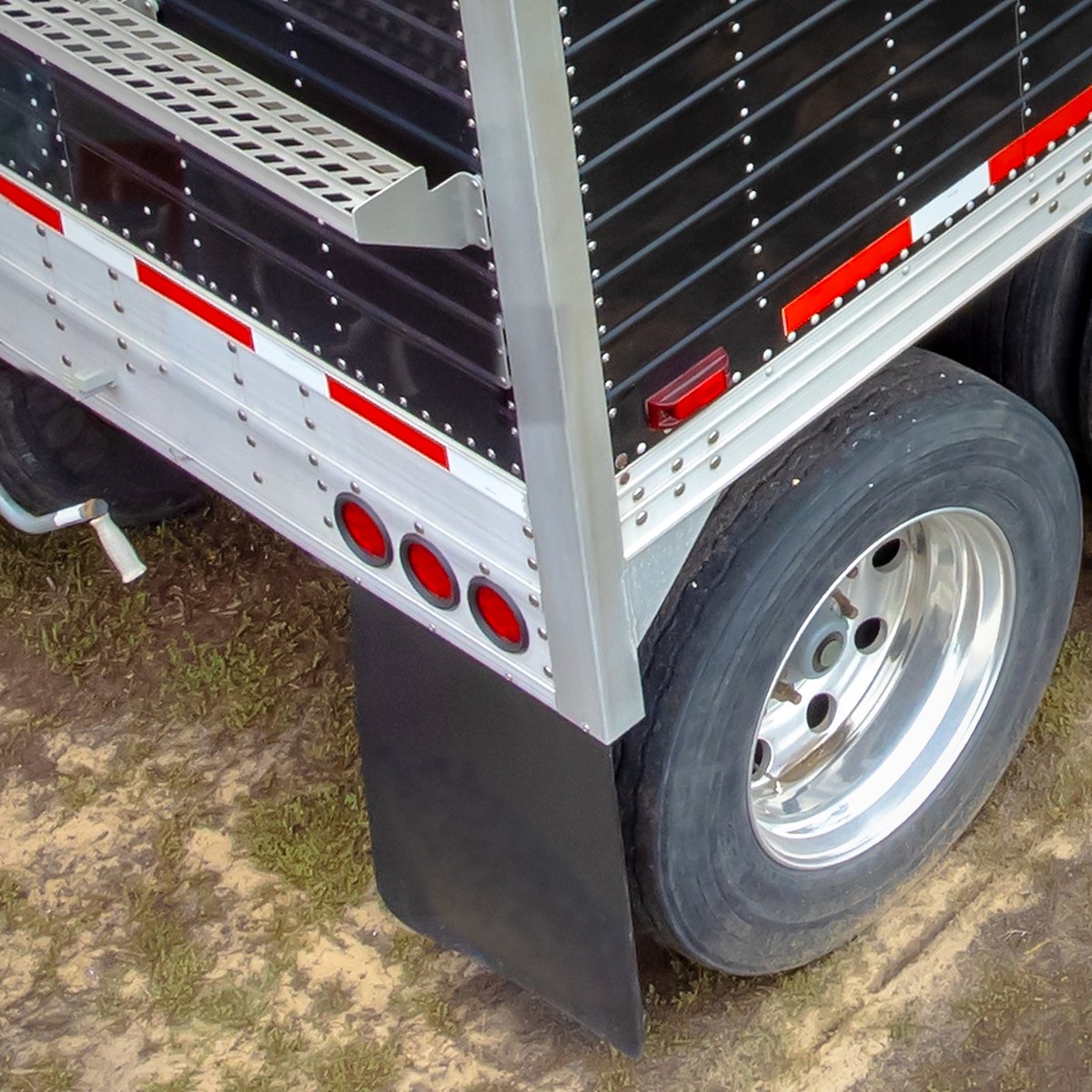 Close view of a plain black rubber mud flap behind a trailer wheel