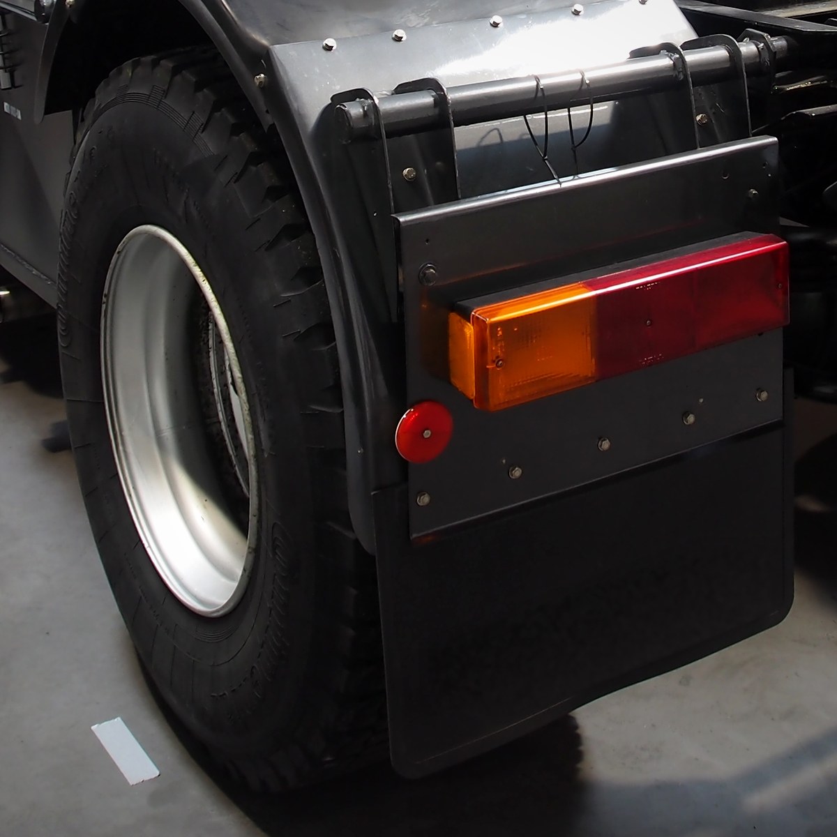 Plain black rubber mud flap and tail light at the rear of a tractor